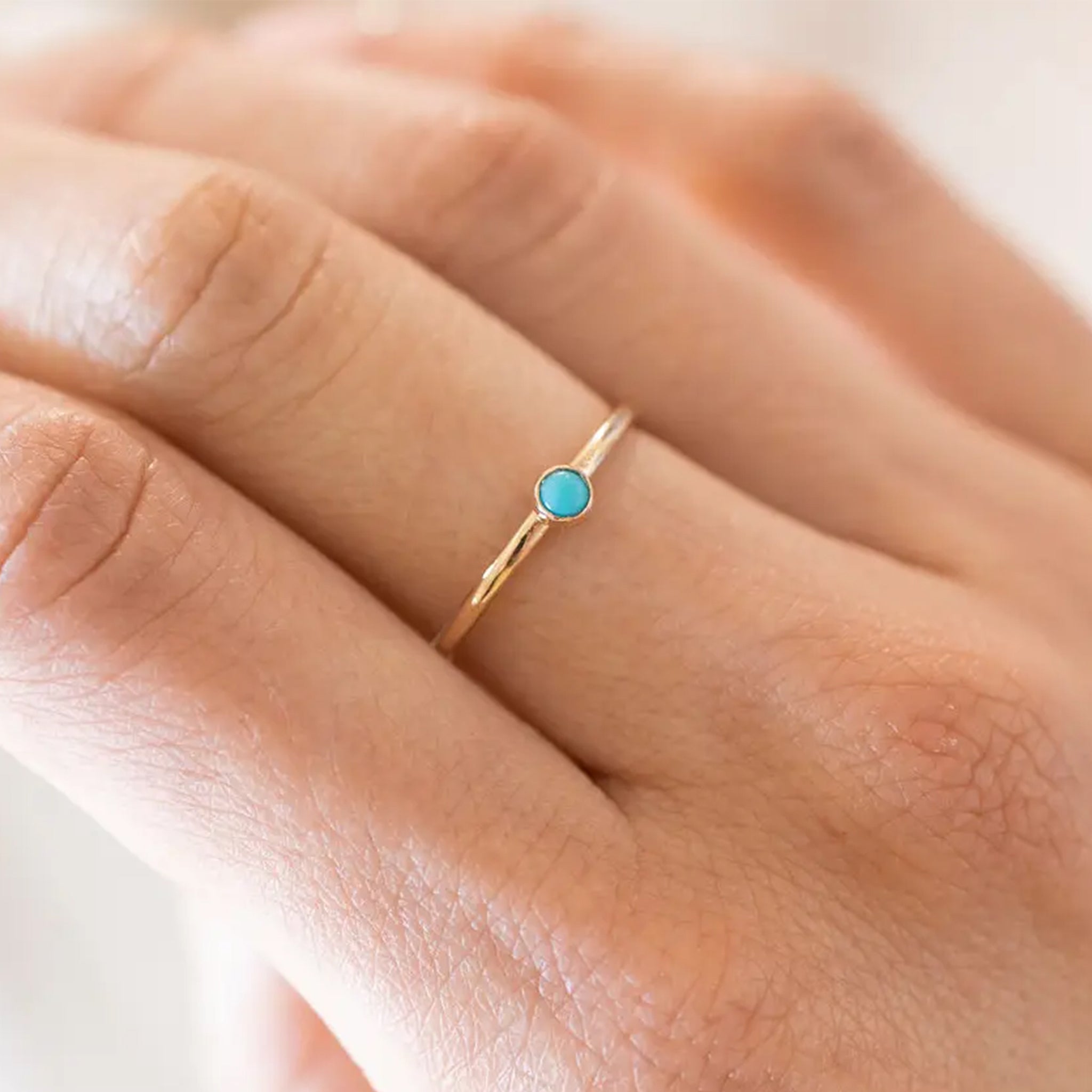 A gold thin band ring with a single mini turquoise stone in the center. 