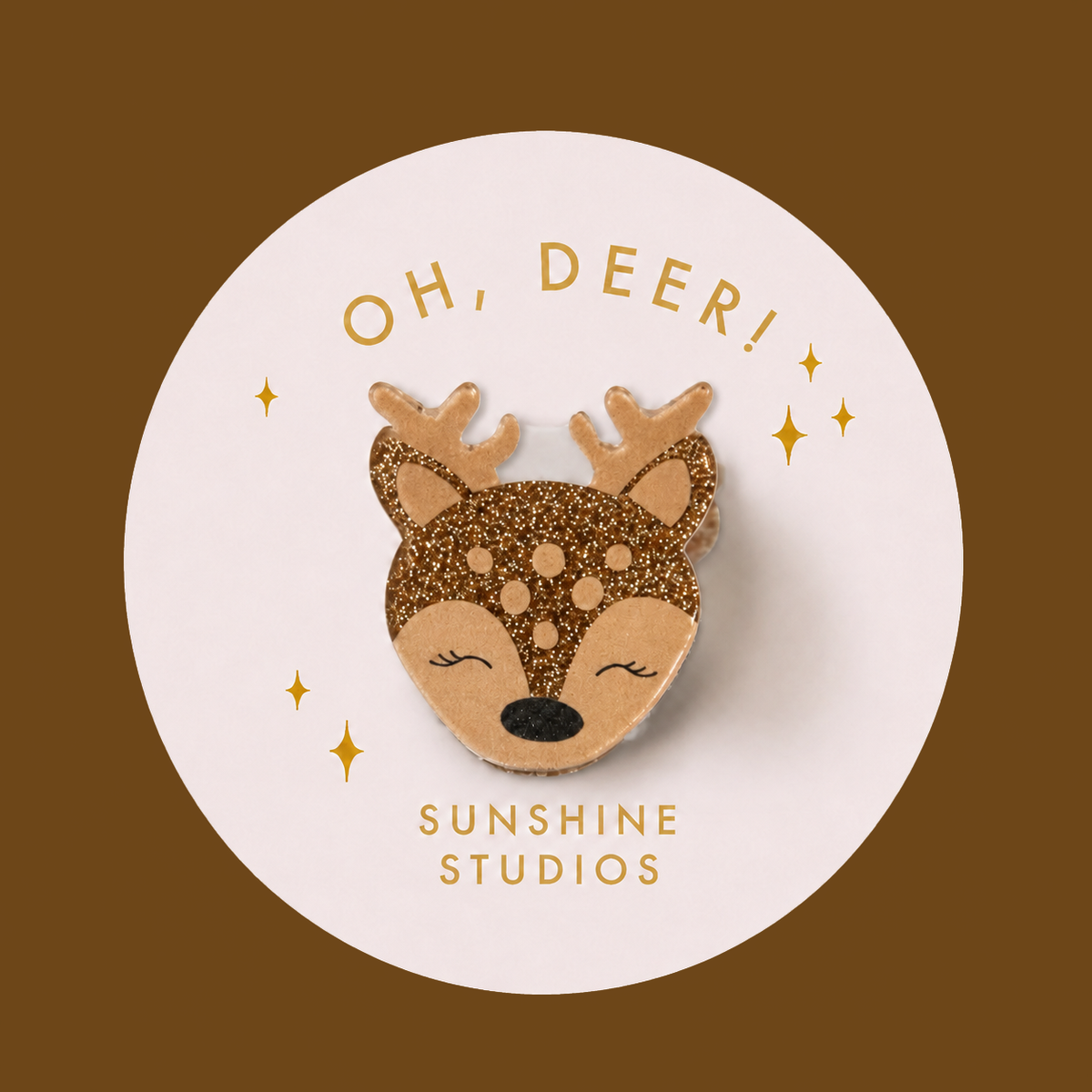 A cute deer head mini hair clip with a glittery brown and beige pattern, displayed on a white circular backing card that reads 'OH, DEER! SUNSHINE STUDIOS' against a solid brown background.