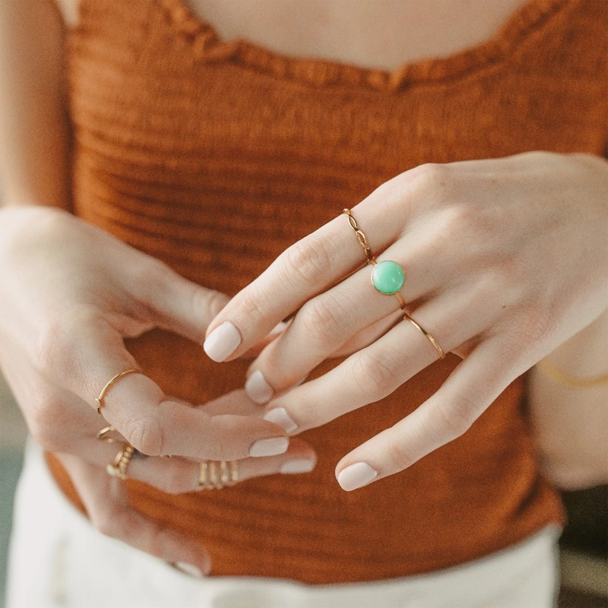 A minimal gold band ring worn on a model with their other rings. 
