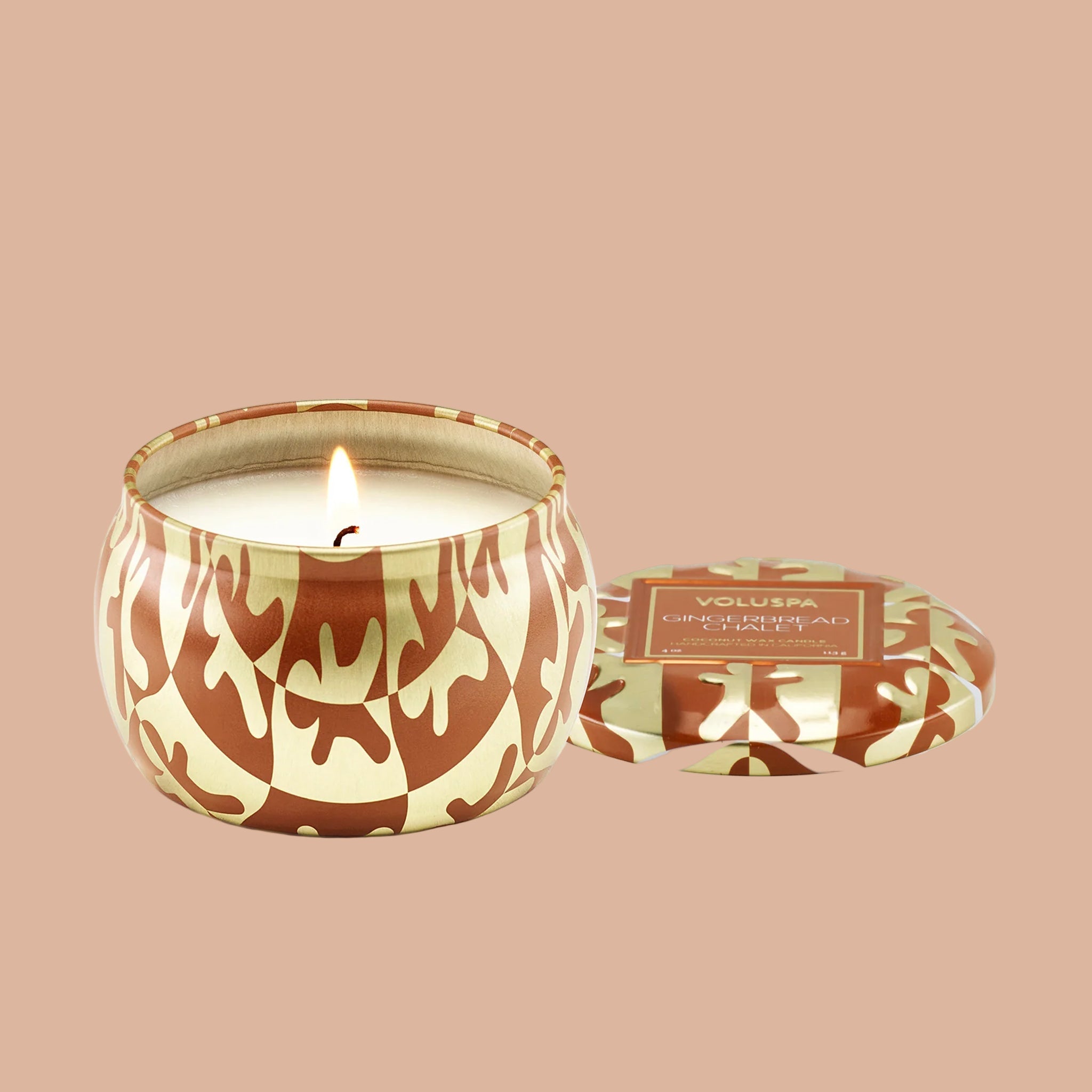 A small tin candle with a brown and gold wavy gingerbread shaped pattern. 
