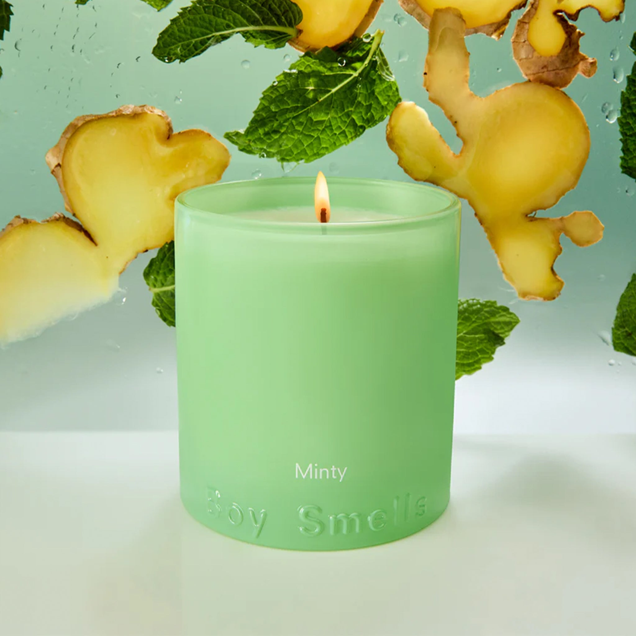 A green glass candle with text that reads, 'Minty Boy Smells'. 