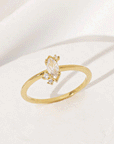 On a white background is a gold ring with a marquise shaped cubic zirconia with three smaller stones, two towards the bottom and on the top. 