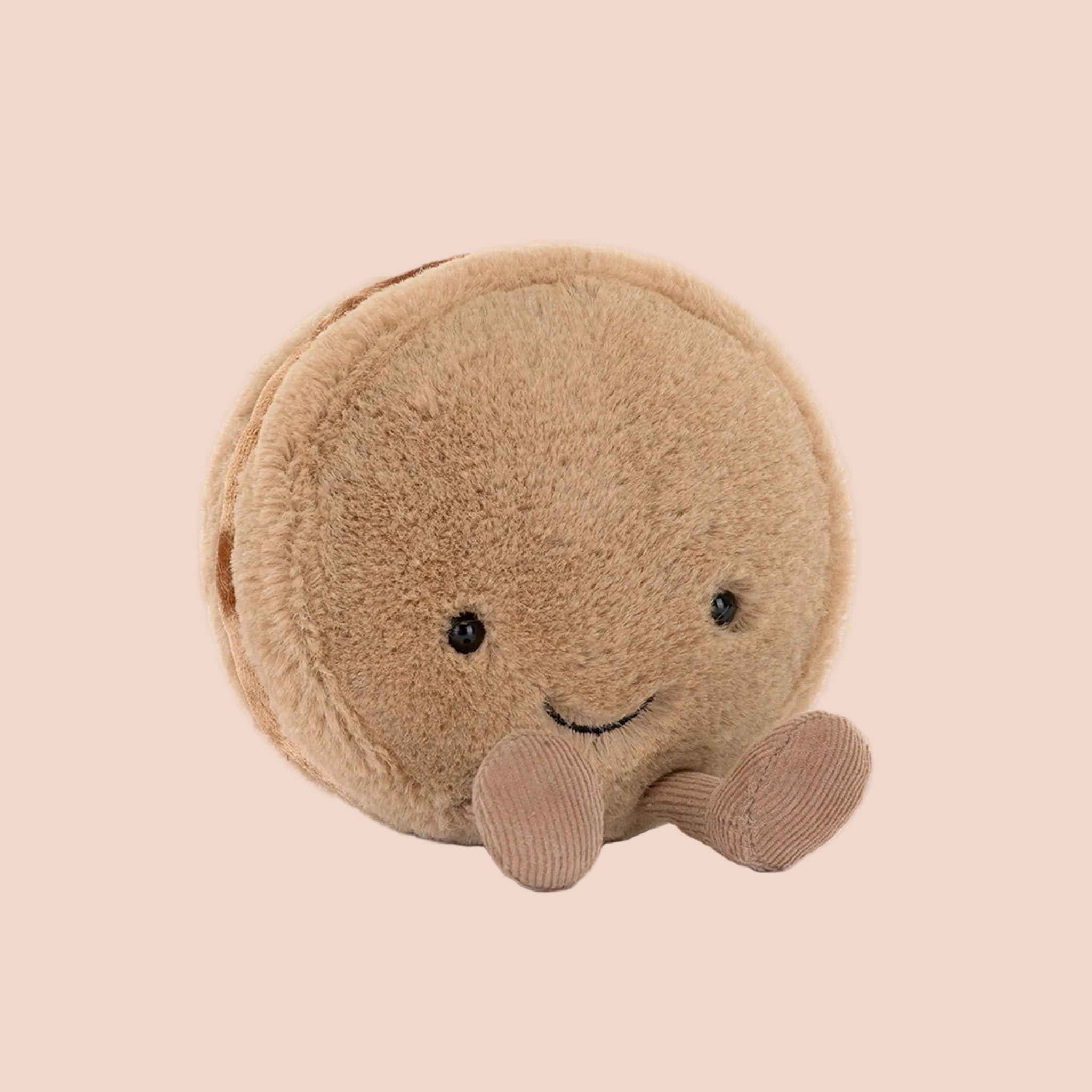 A brown macaron shaped stuffed toy with a smiling face and brown corduroy legs and feet. 