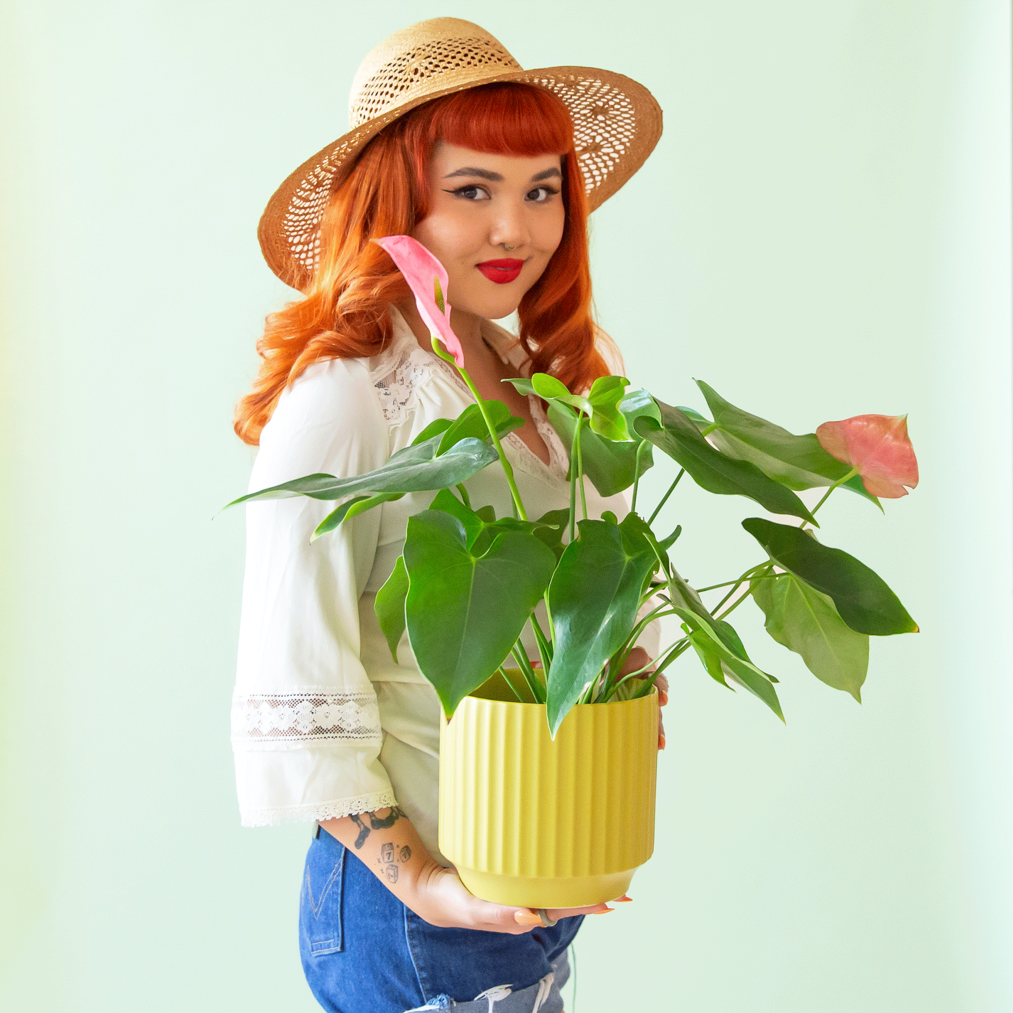 A model holding the ribbed chartreuse planter filled with a pink and green anthurium inside. 