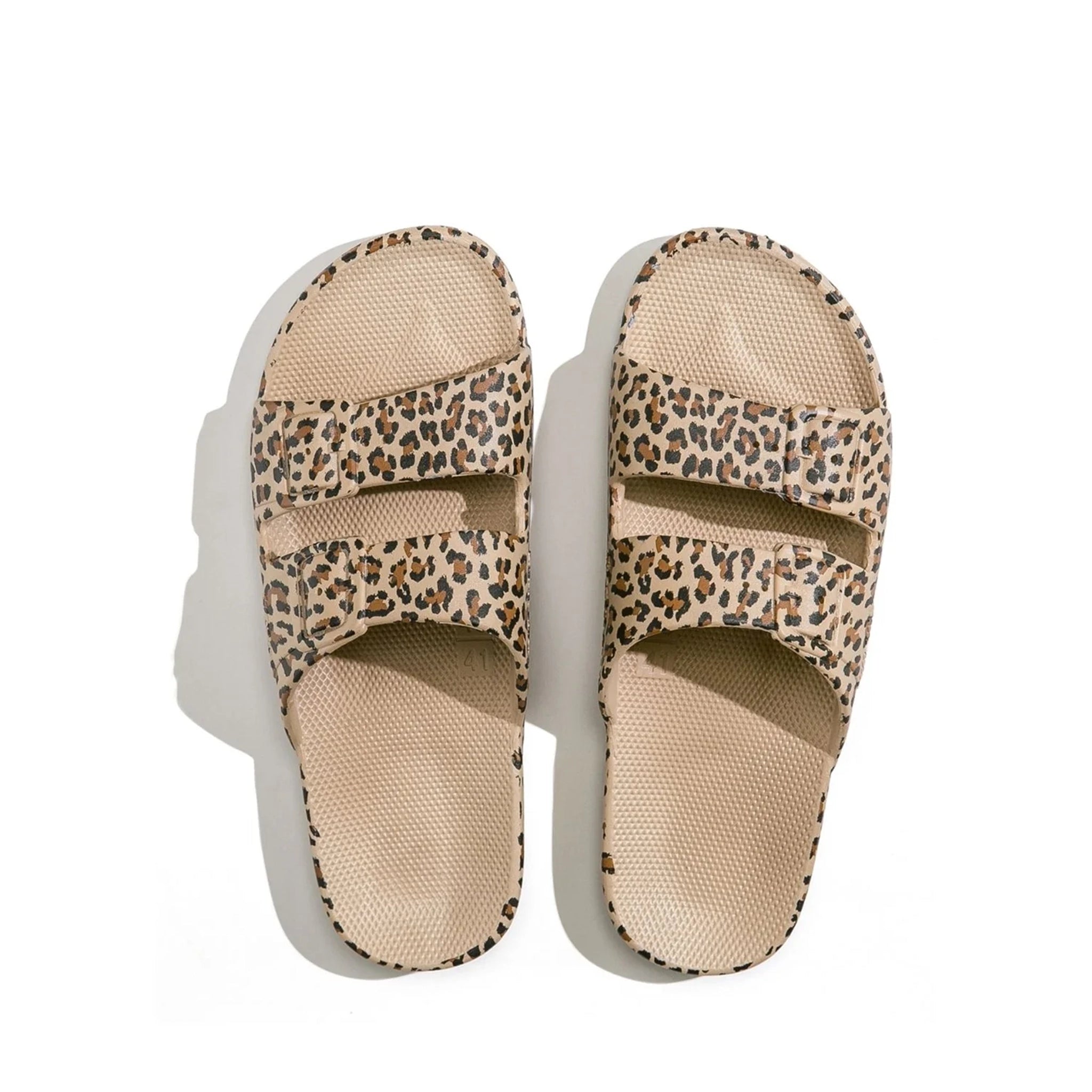 On a white background is a tan leopard print pair of cloud slides with two straps going across the front. 