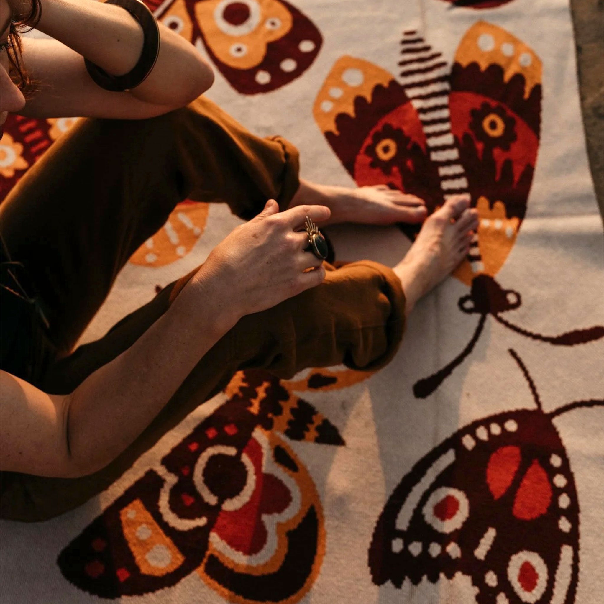 A neutral blanket with an orange and brown moth design. 