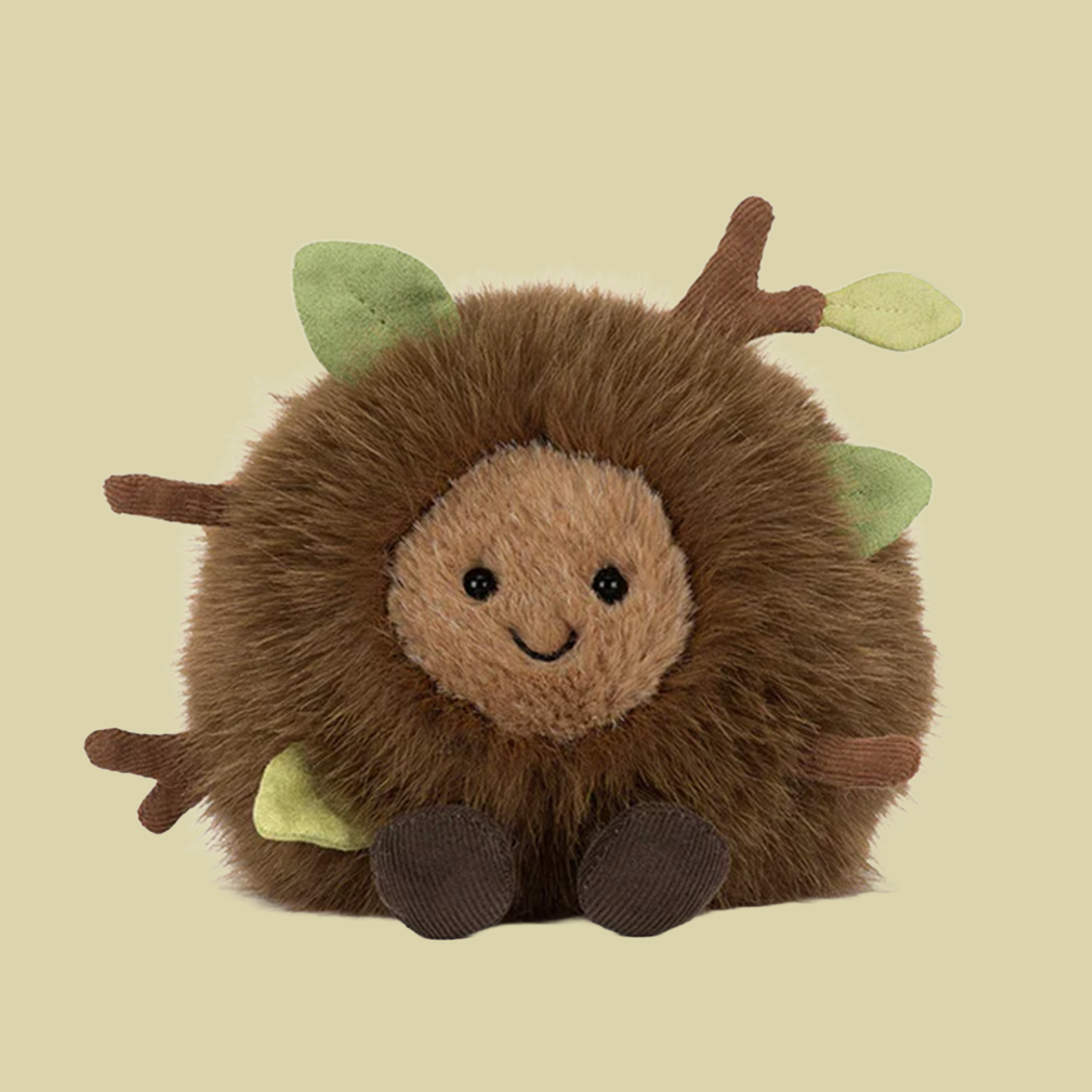 Plush woodland hedgehog stuffed toy with soft brown fur, a smiling face, and small fabric leaves and branches tucked into its coat.