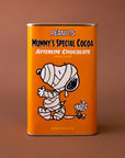 An orange rectangle tin of hot chocolate mix with a graphic of the Snoopy character wrapped up like a mummy and text that reads, 'Peanuts Mummy's Special Cocoa Afterlife Chocolate'. 