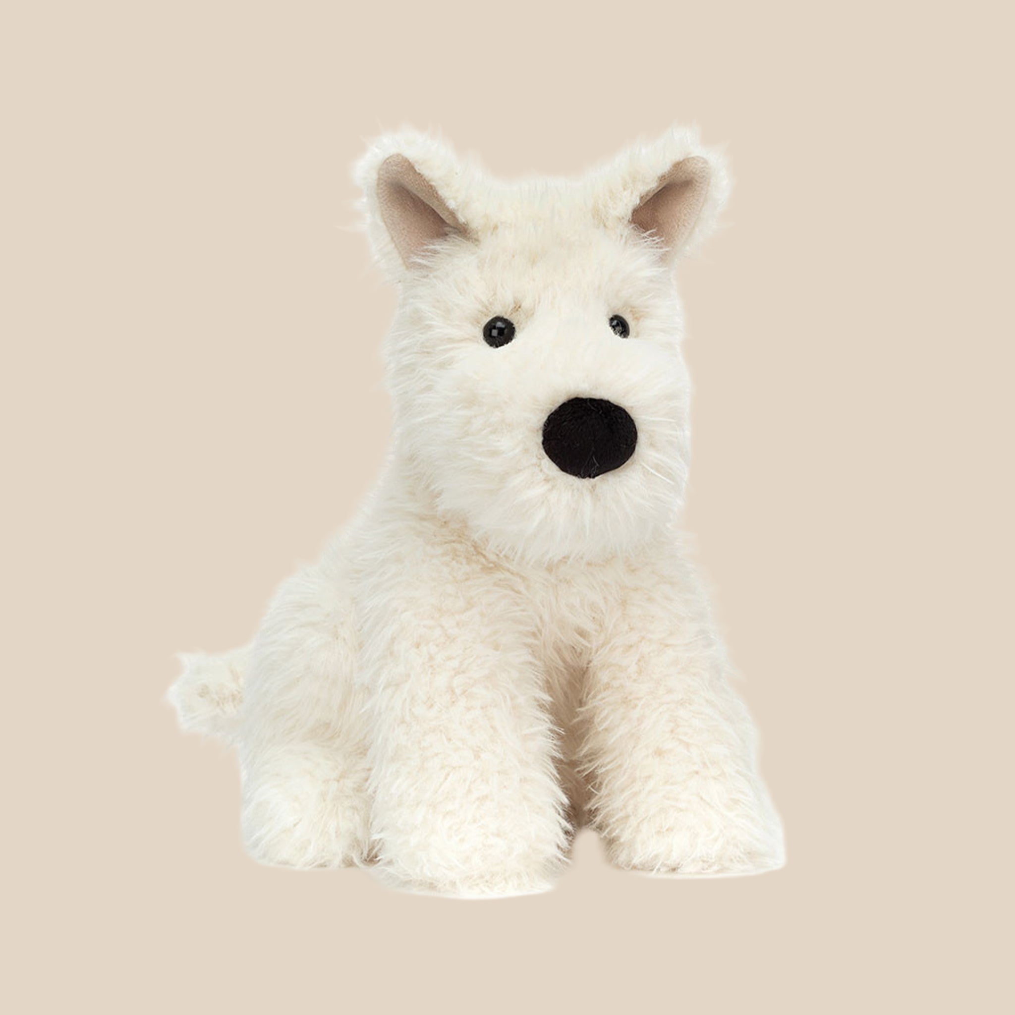 A cream colored scottie dog shaped stuffed toy. 