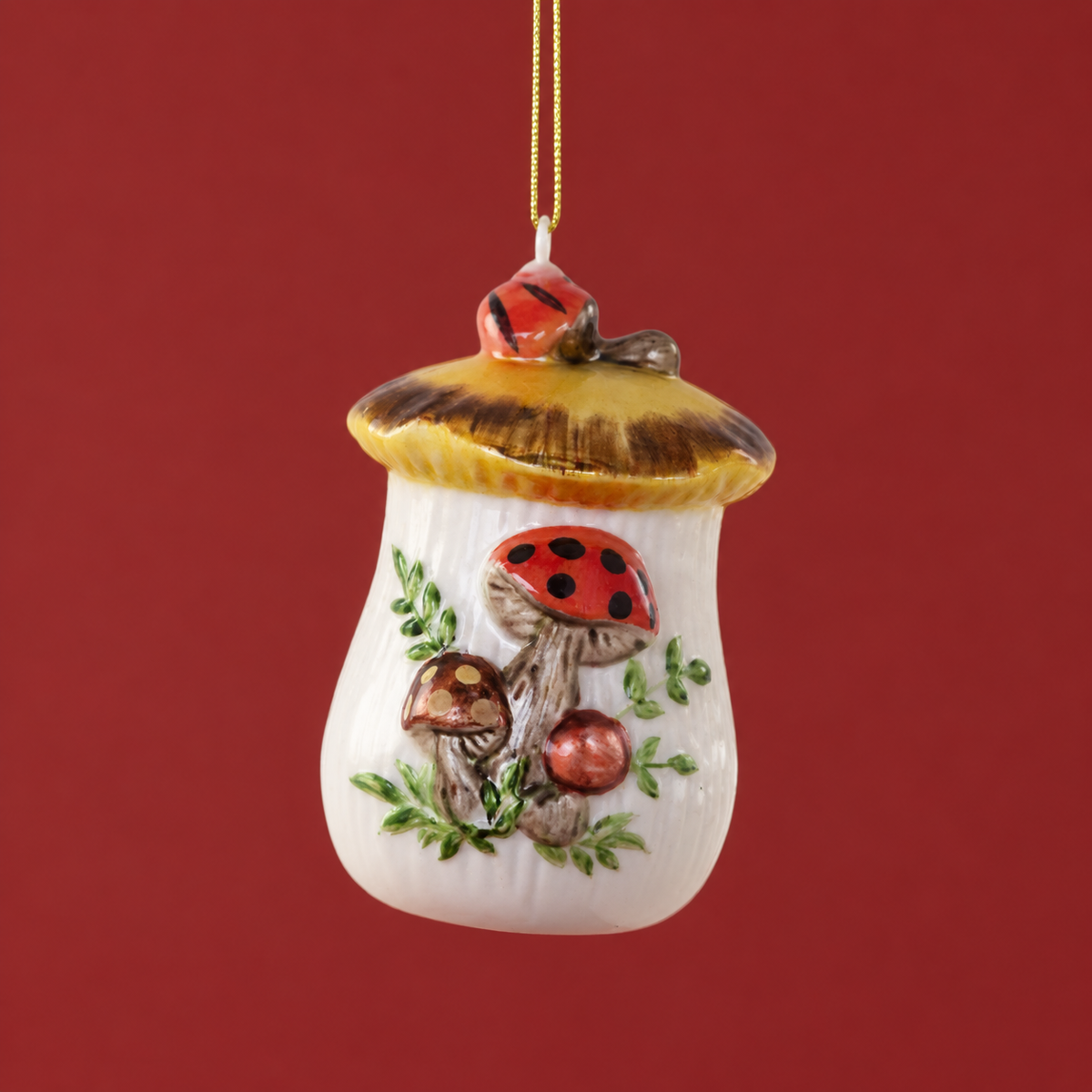 On a green background is an ivory and red glass ornament in the shape of a cookie jar with a mushroom design on it.