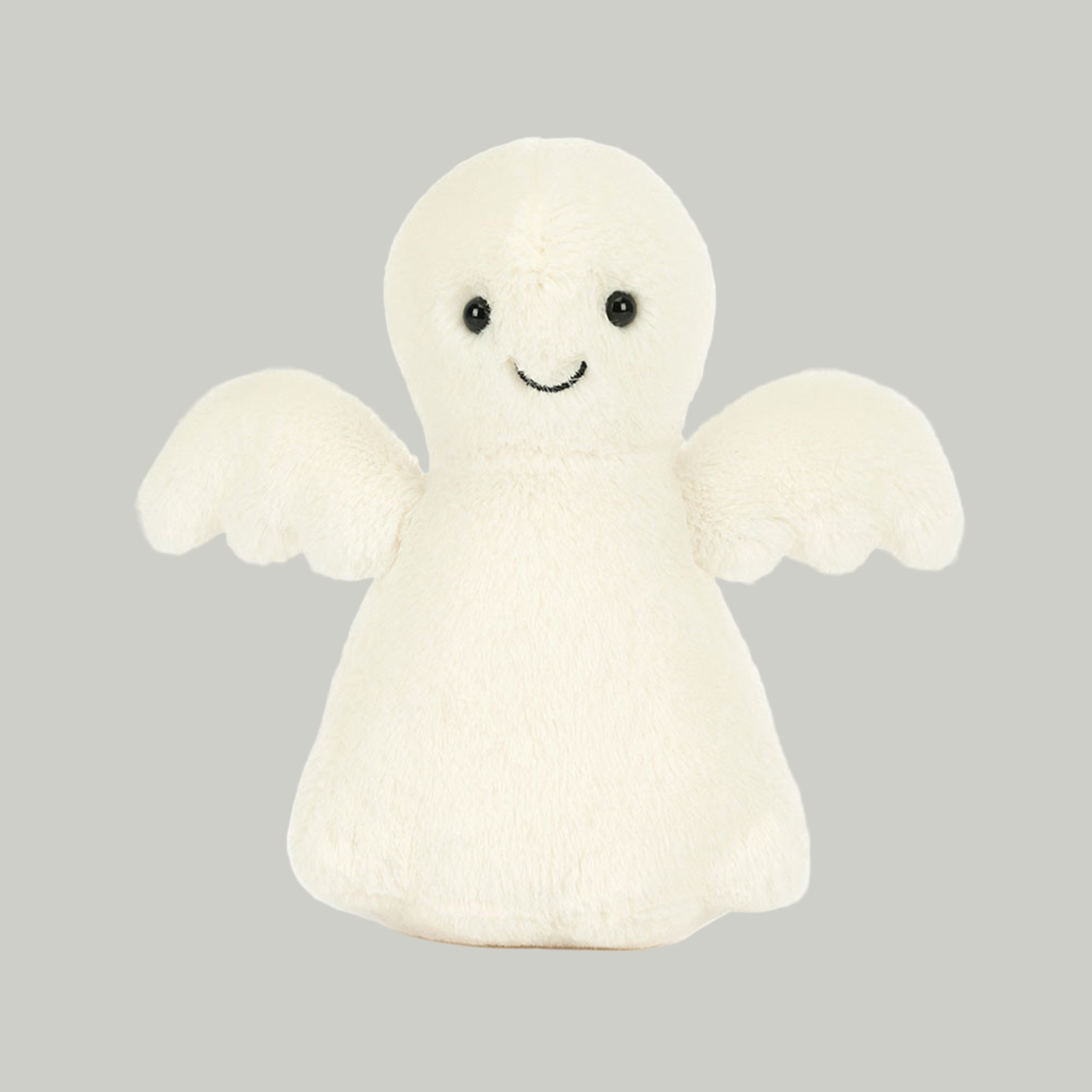 An ivory ghost shaped stuffed toy with a smiling face. 