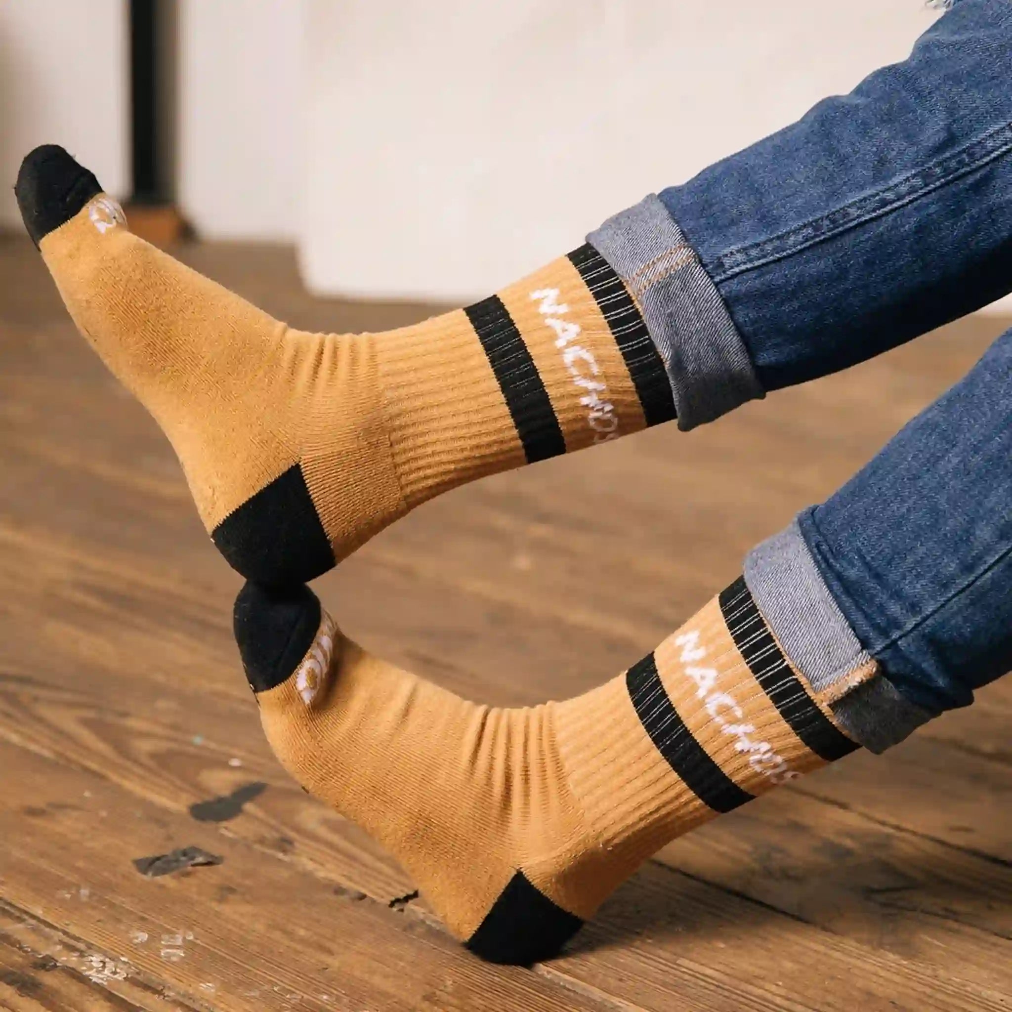 Tan crew socks with black detailing and two black stripes across the top and says &quot;Nachos&quot; in white text.