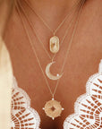A gold necklace with a moon shaped pendant and a cz stone on the edge. 