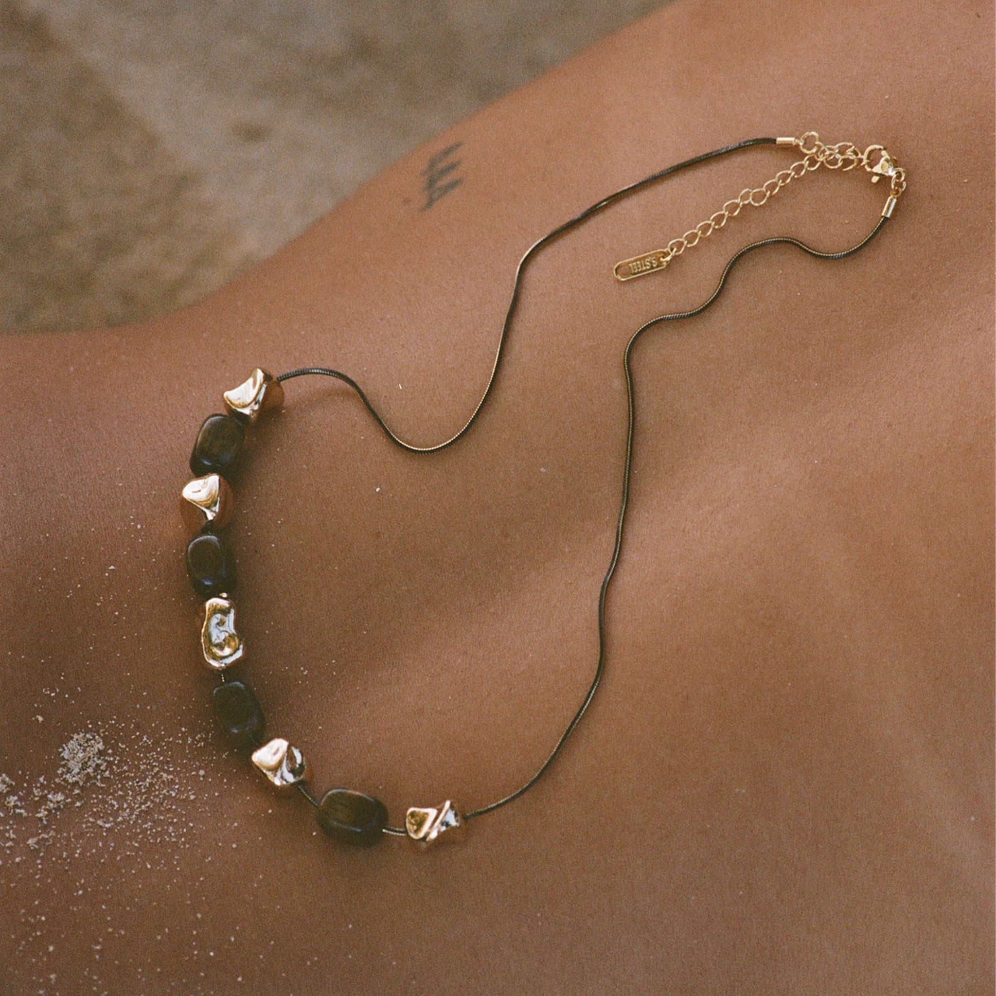 Necklace with green beads and gold accents on a person's neck