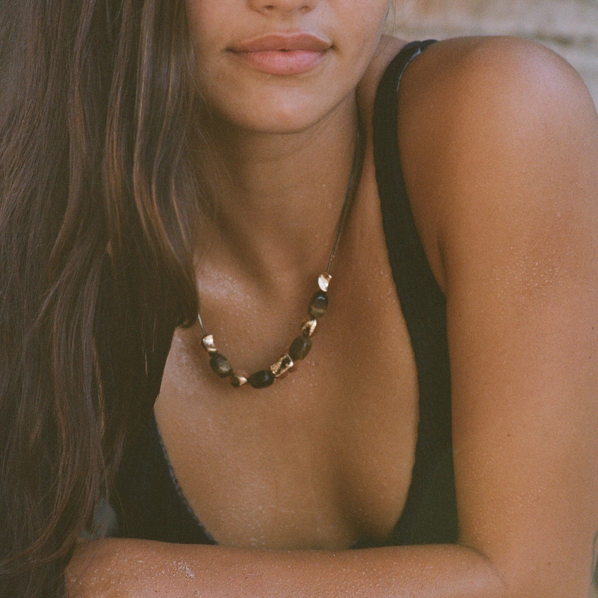 Necklace with green beads and gold accents on a person's neck