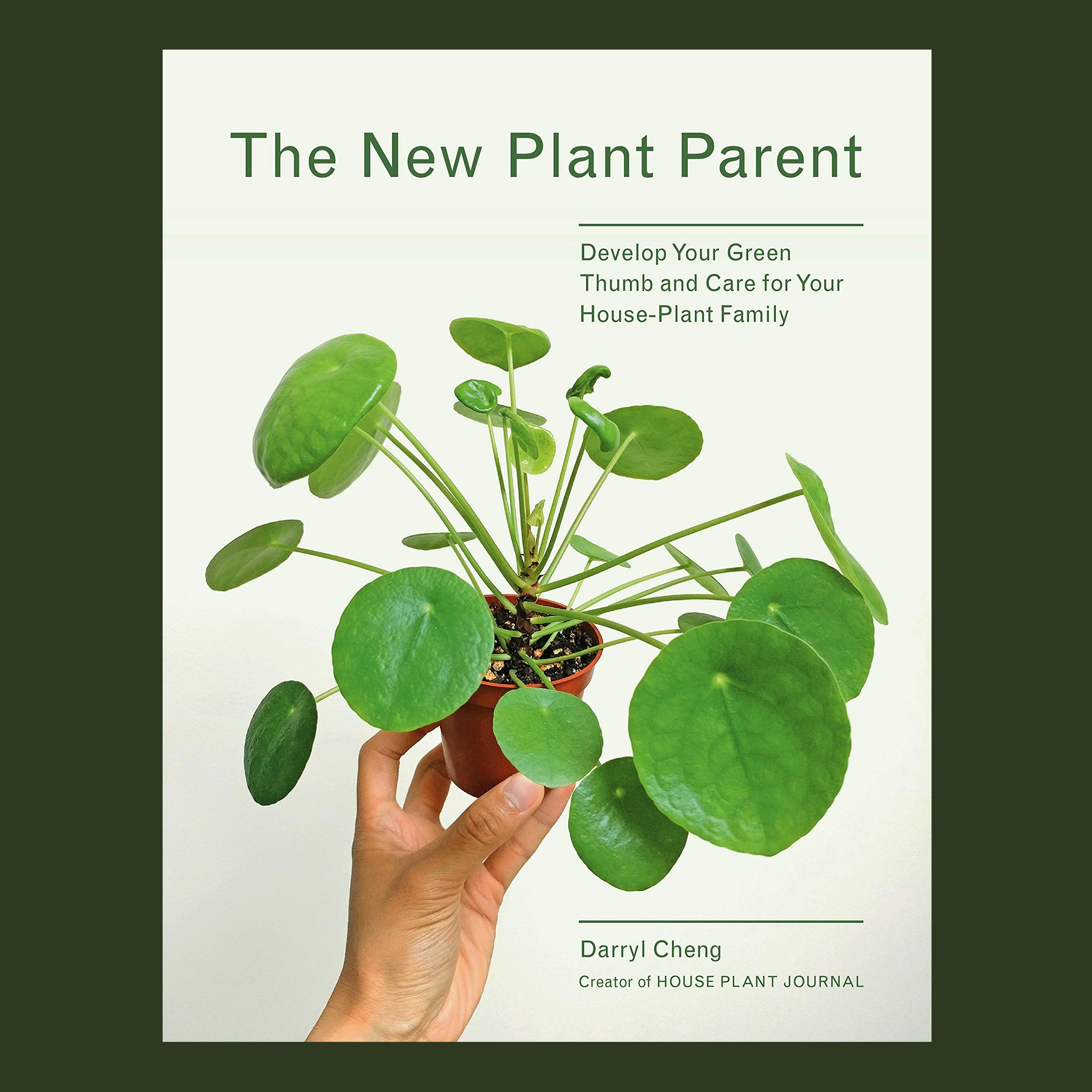 This book has a white cover reading 'The New Plant Parent' across the top of the cover. A forest green Peperomioide plant with circular leaves and long stems is held in the center. 