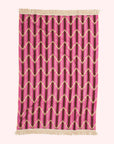 A pink chevron print towel with an ivory tassel edge on two sides. 