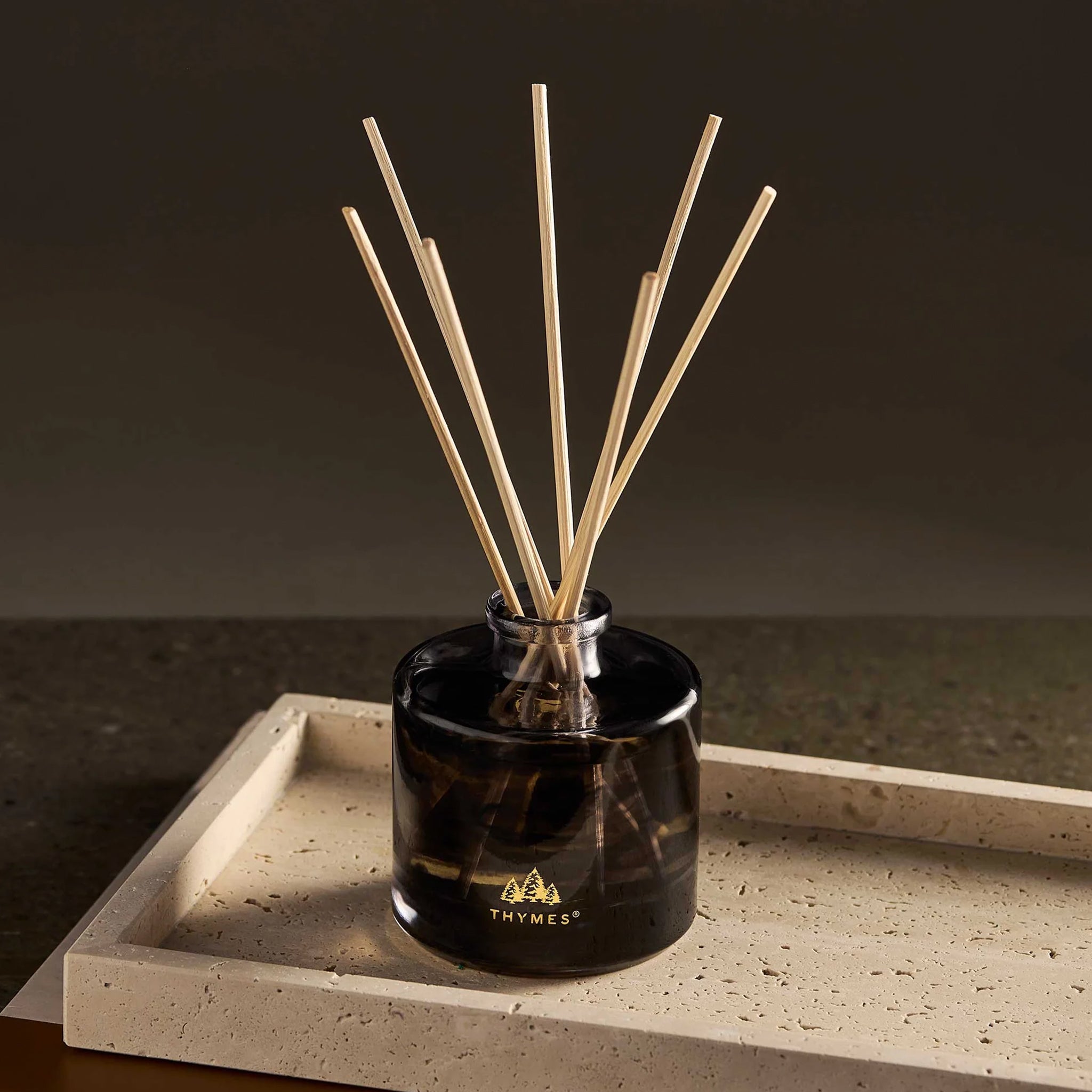A diffuser with black glass and wooden reeds. 