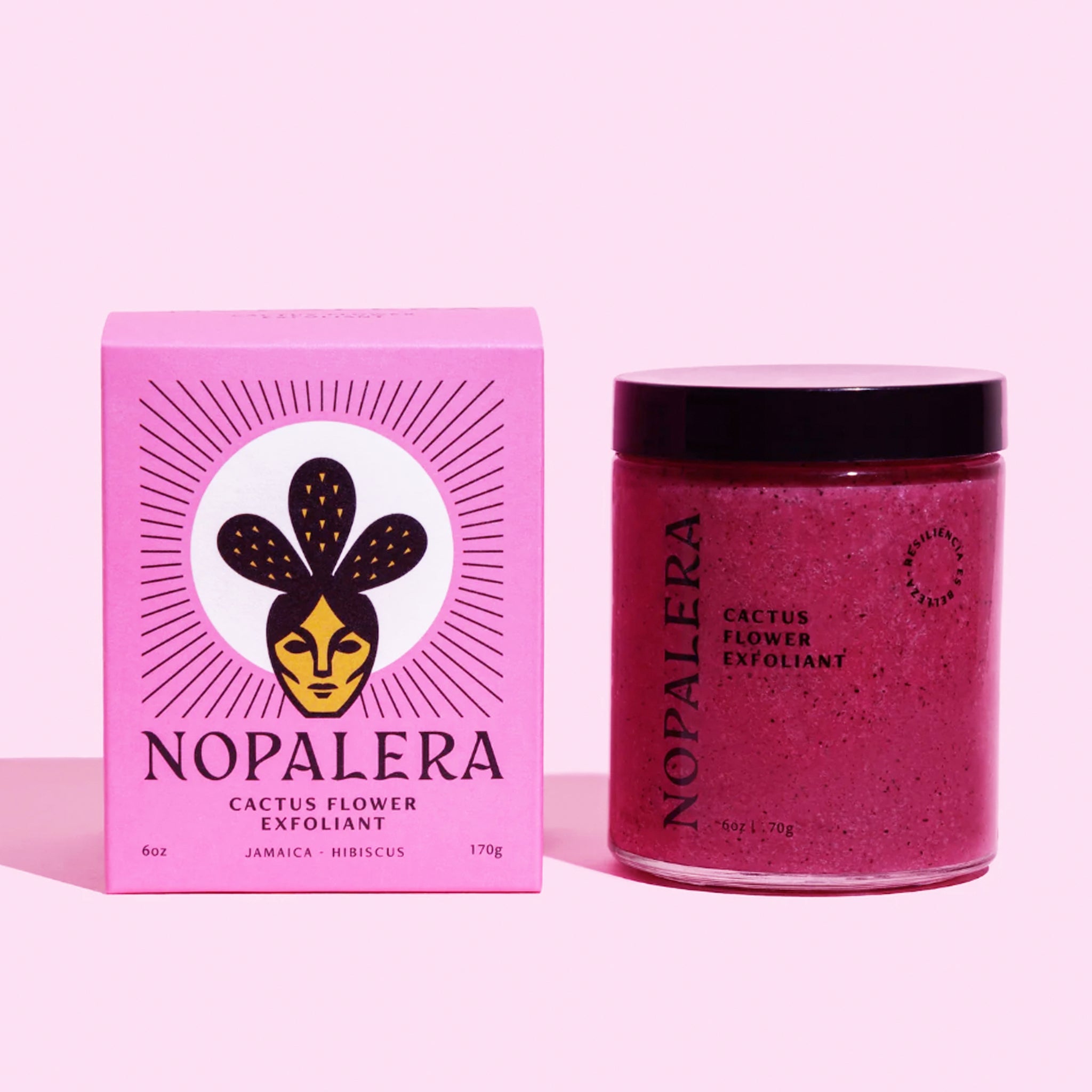 On a pink background is a jar of hot pink body scrub next the pink packaging it comes in. 