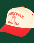 A cream and red trucker hat with embroidered text that reads, "North Pole Social Club". 