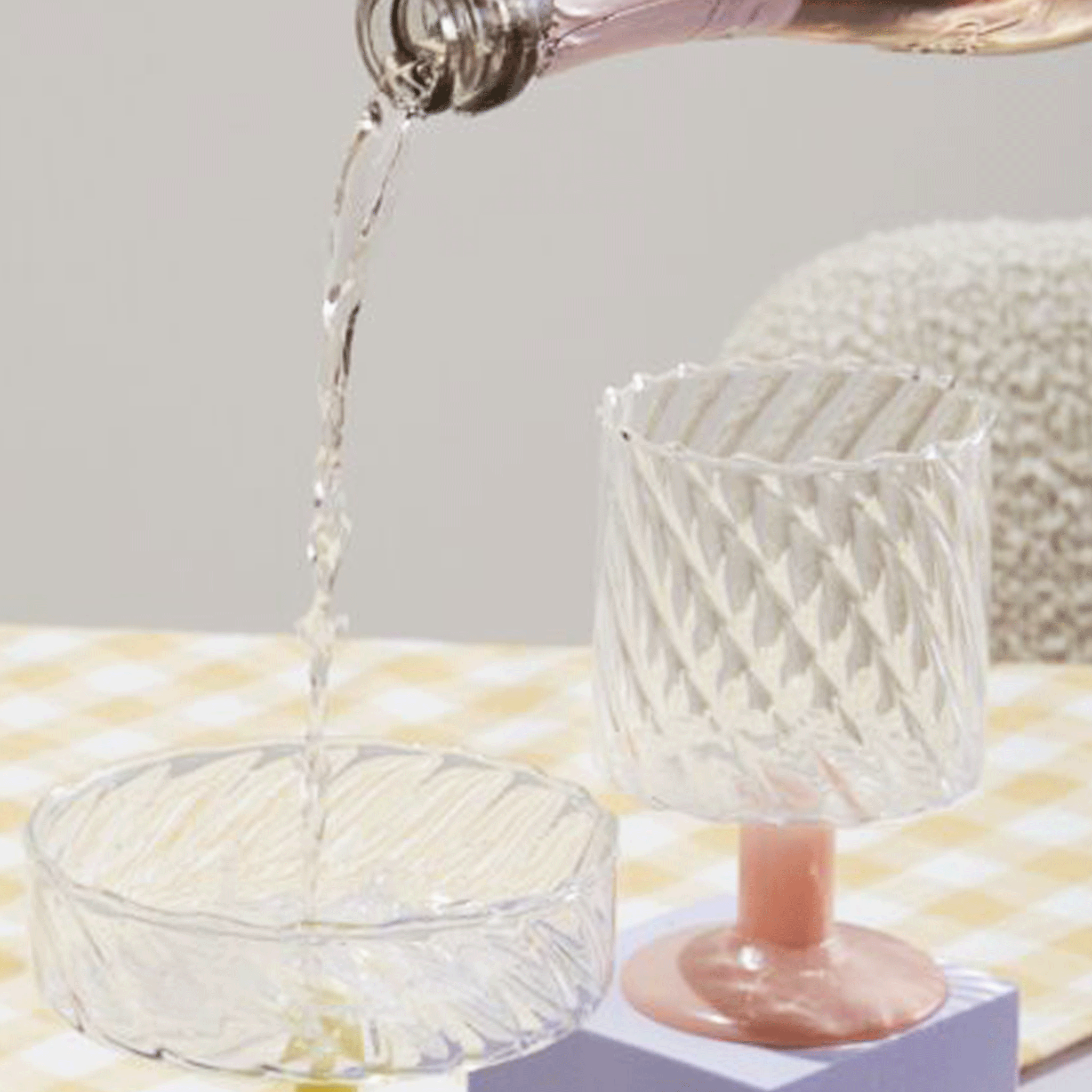 A wavy glass wine glass with a pink short stem.