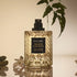 A clear bottle of perfume with a black label in the center that reads, 'Voluspa Nude Effect'. 