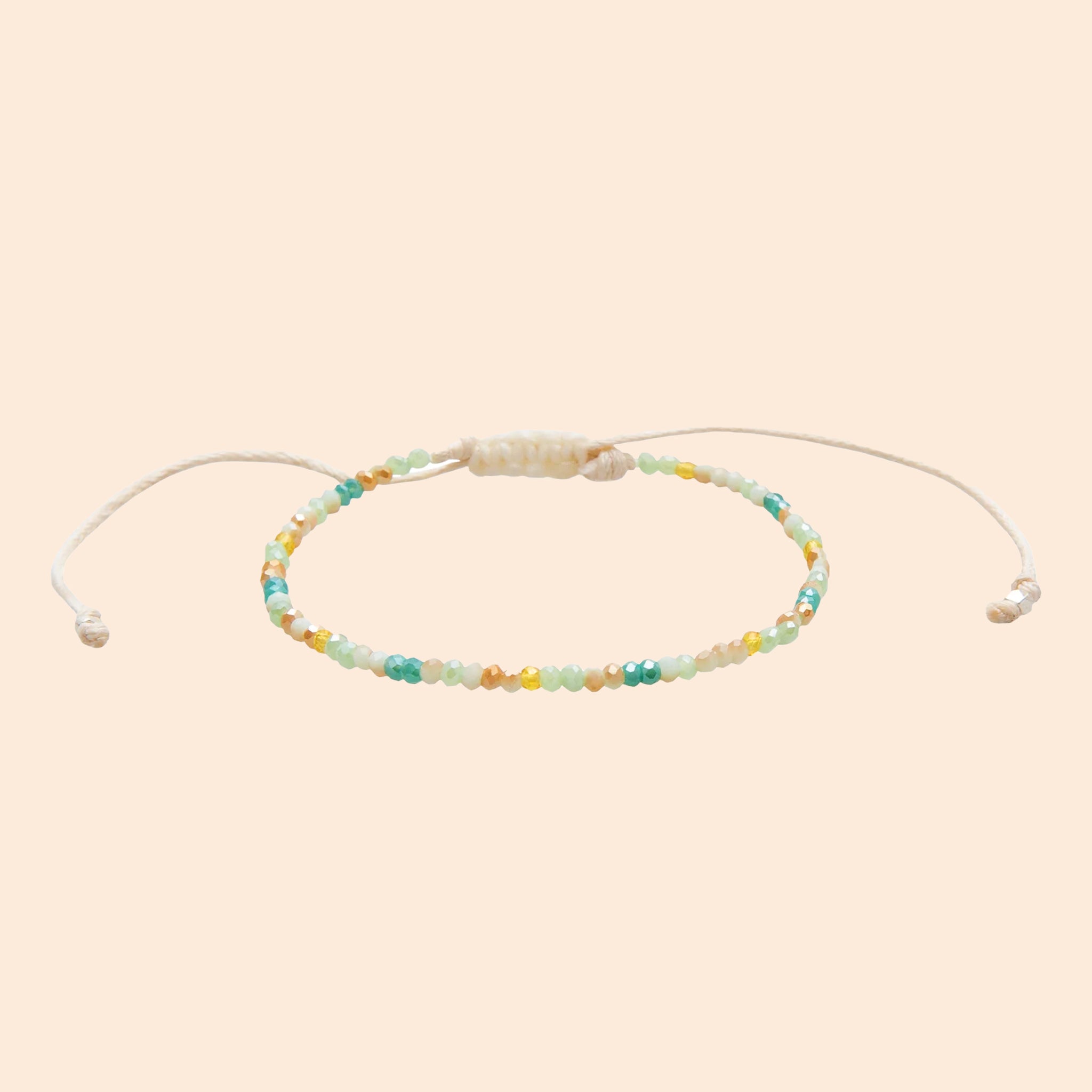 Teal, neutral and yellow beads strung to make a bracelet with an adjustable cord.