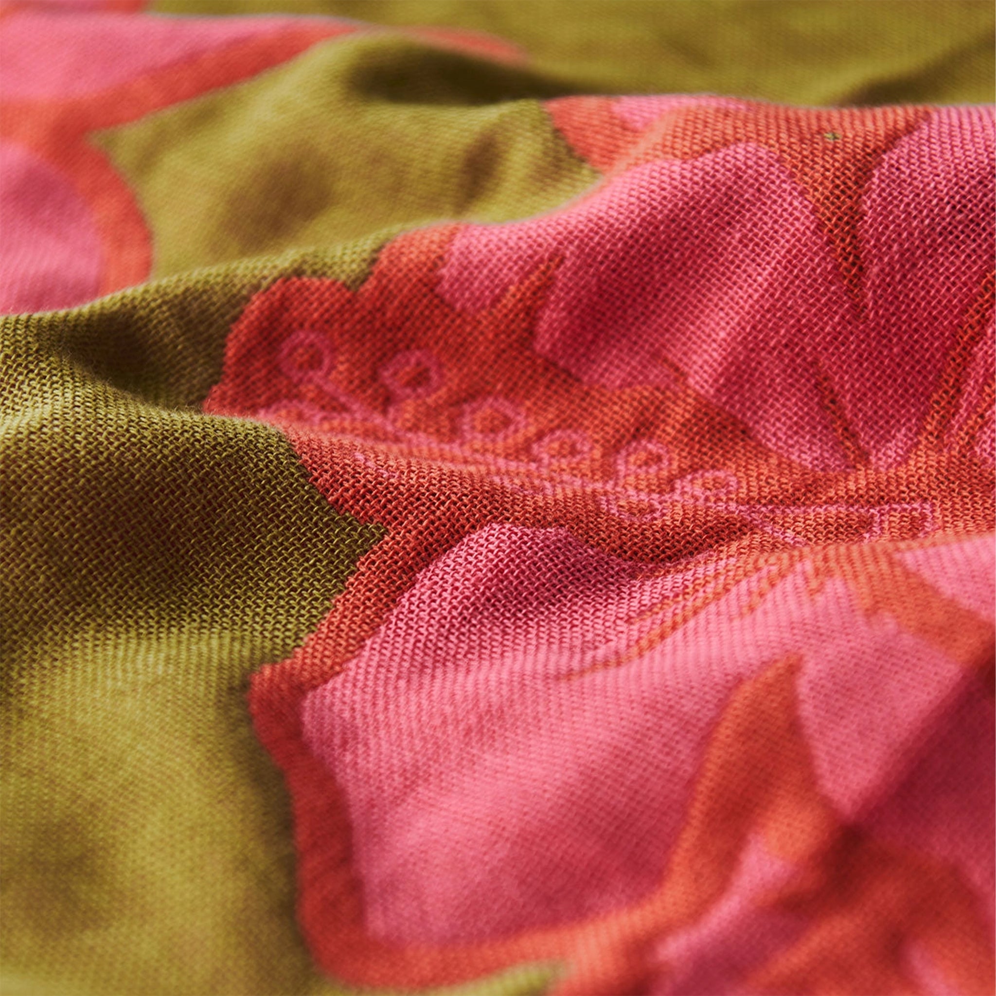 A green and pink tropical floral print beach blanket. 