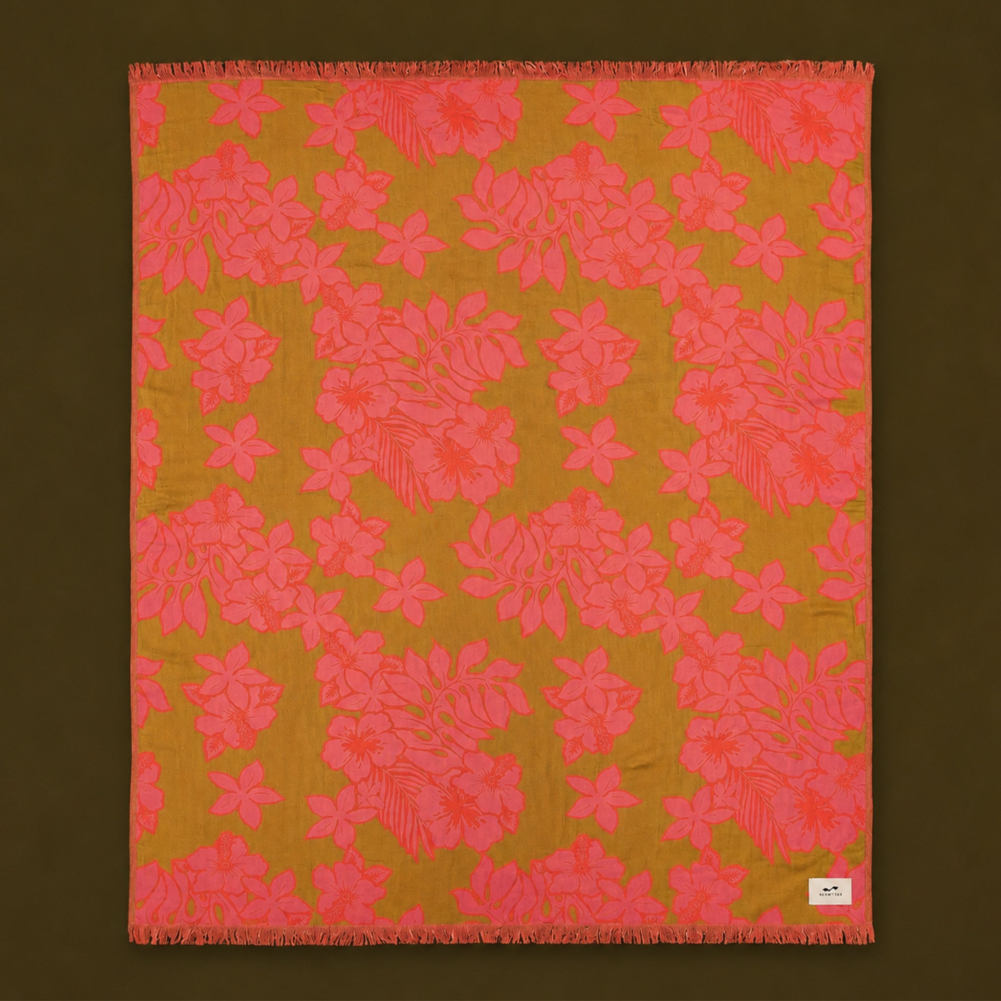 A green and pink tropical floral print beach blanket. 