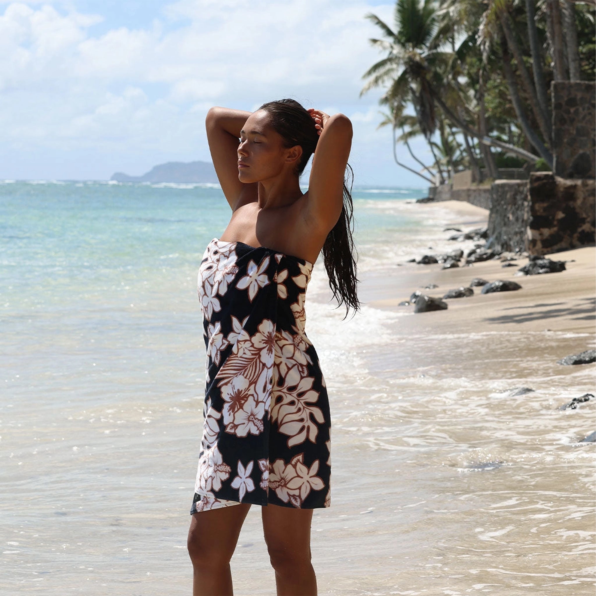 A black, cream and brown tropical print beach towel.