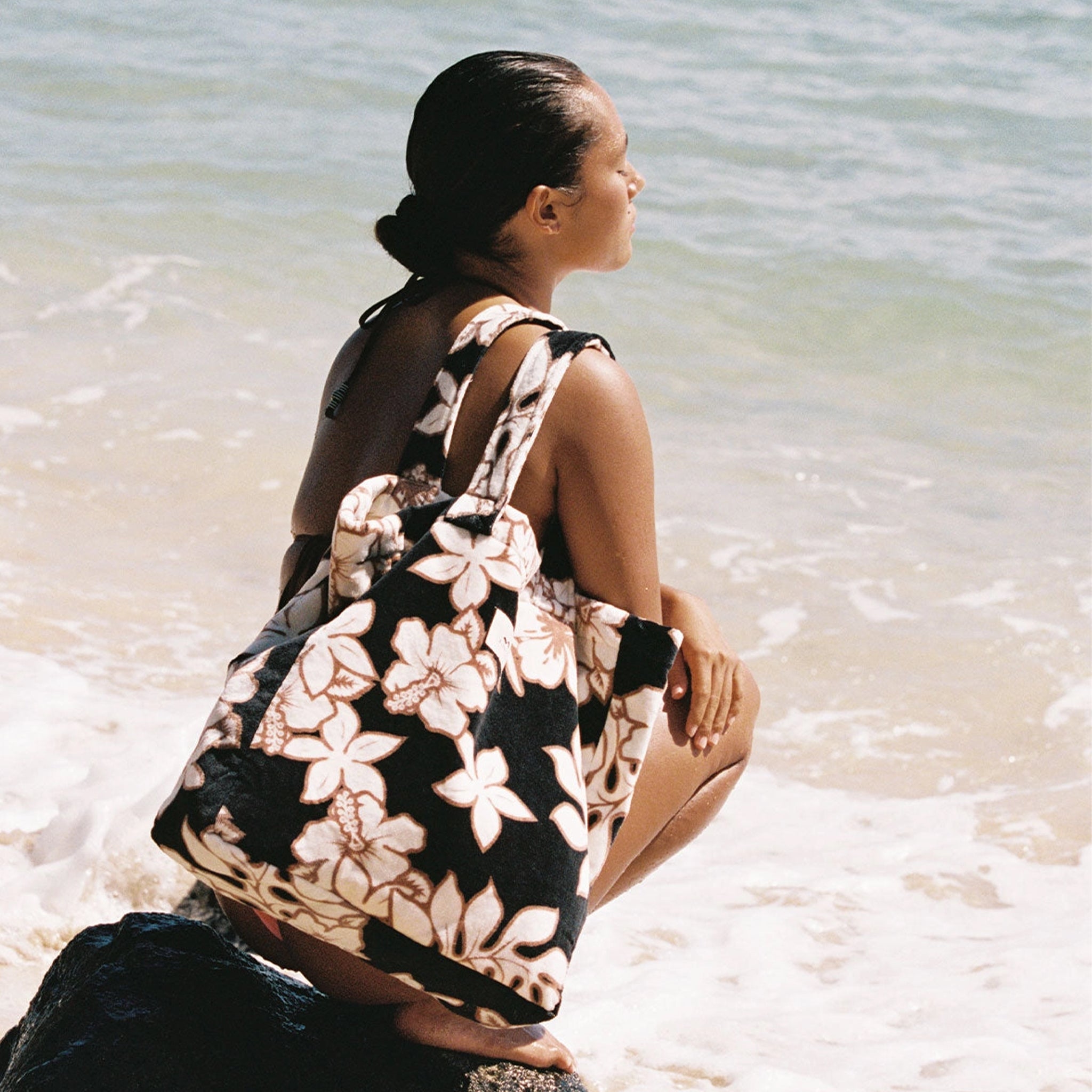 A black, cream and brown terry tote bag with a tropical floral print. 