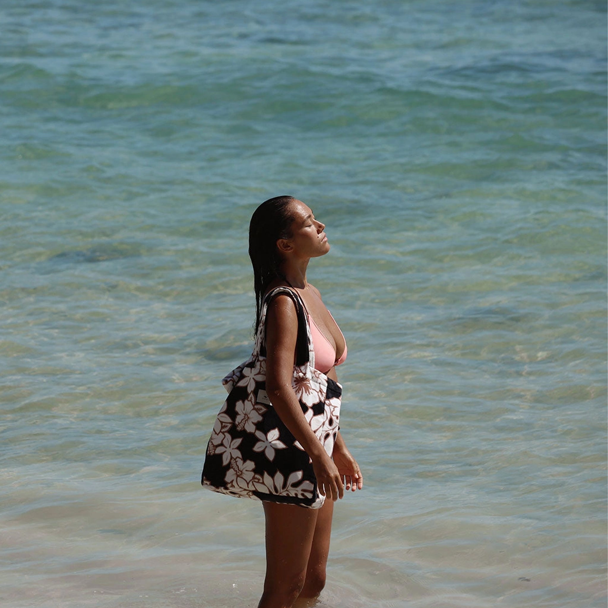 A black, cream and brown terry tote bag with a tropical floral print. 