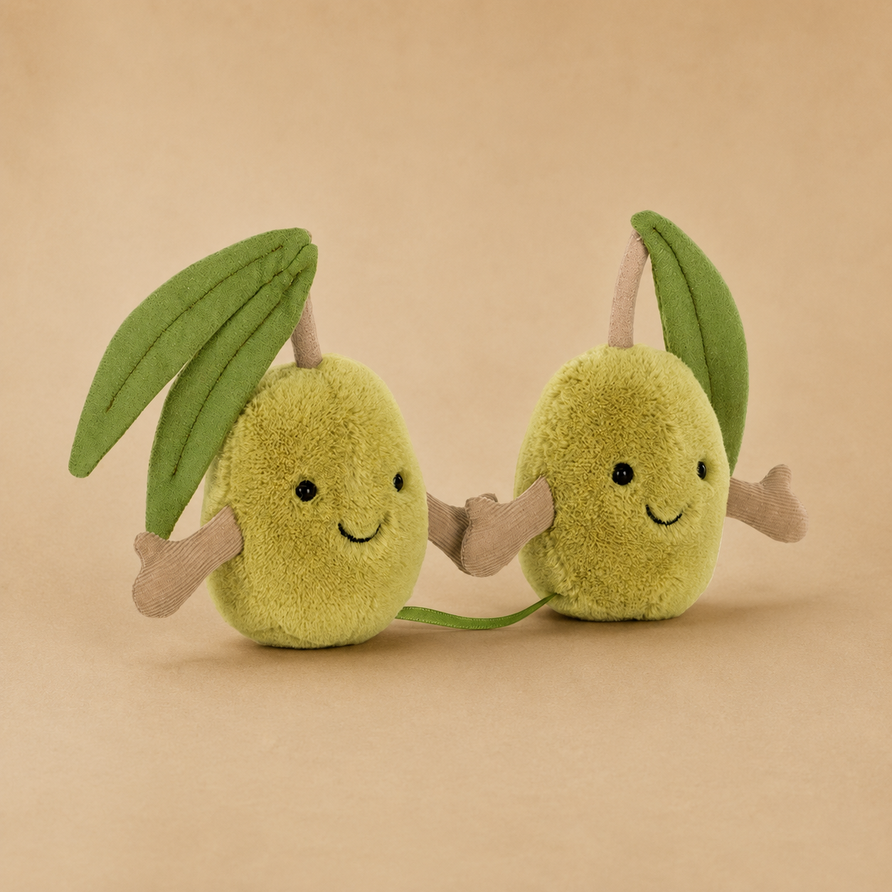 A pair of green olive shaped stuffed toys with smiling faces and hands that connect with velcro. 