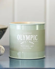 A green tin candle with white text that reads, 'Olympic Pacific Moss'. 