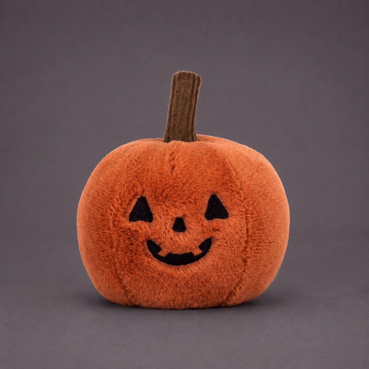 A pumpkin shaped stuffed toy. 