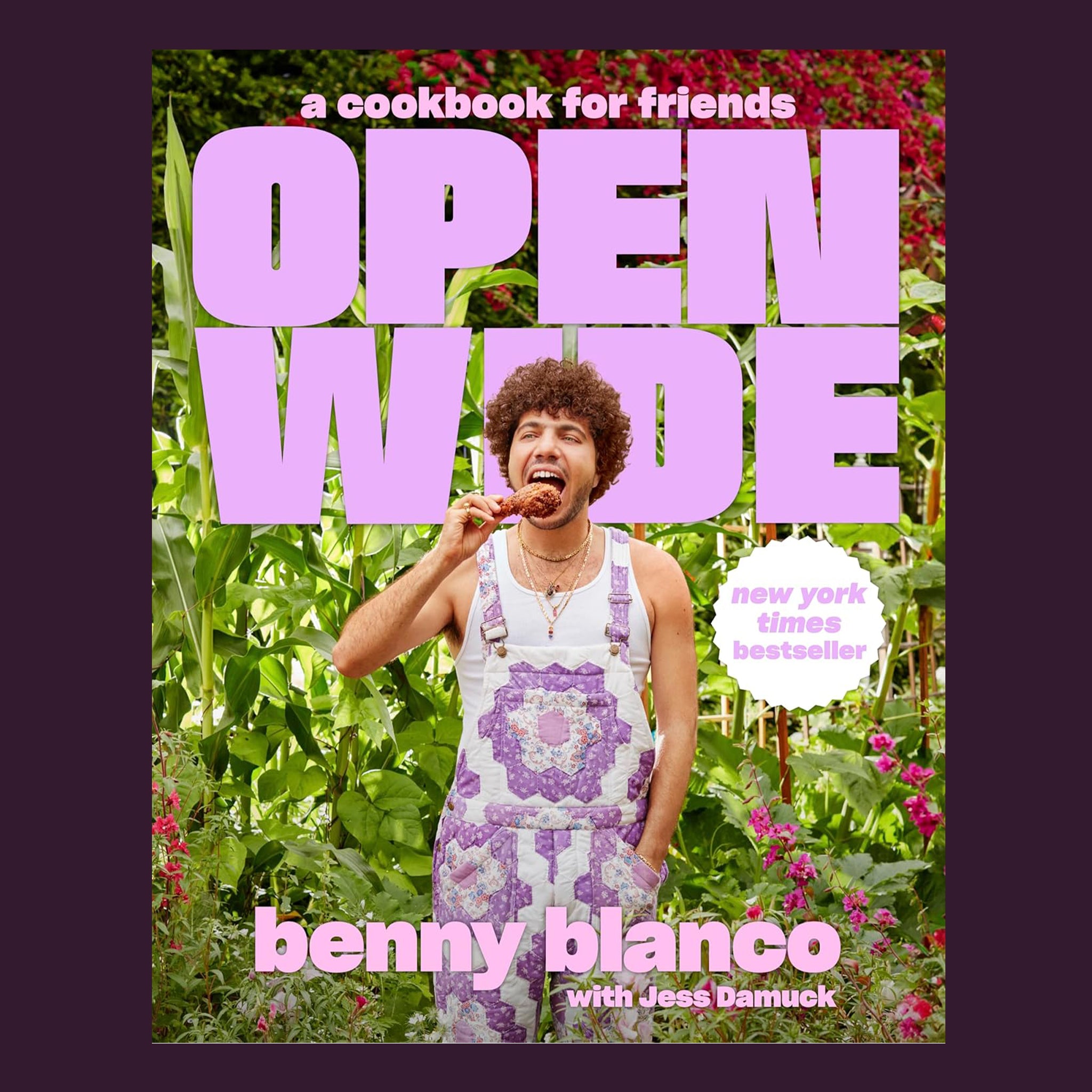 'a cookbook for friends Open Wide' in purple text over a photo of Benny Blanco eating a piece of chicken in purple overalls. 