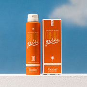 An orange spray bottle of product with text on the front hat reads, 'Vacation Orange Gelee'. 