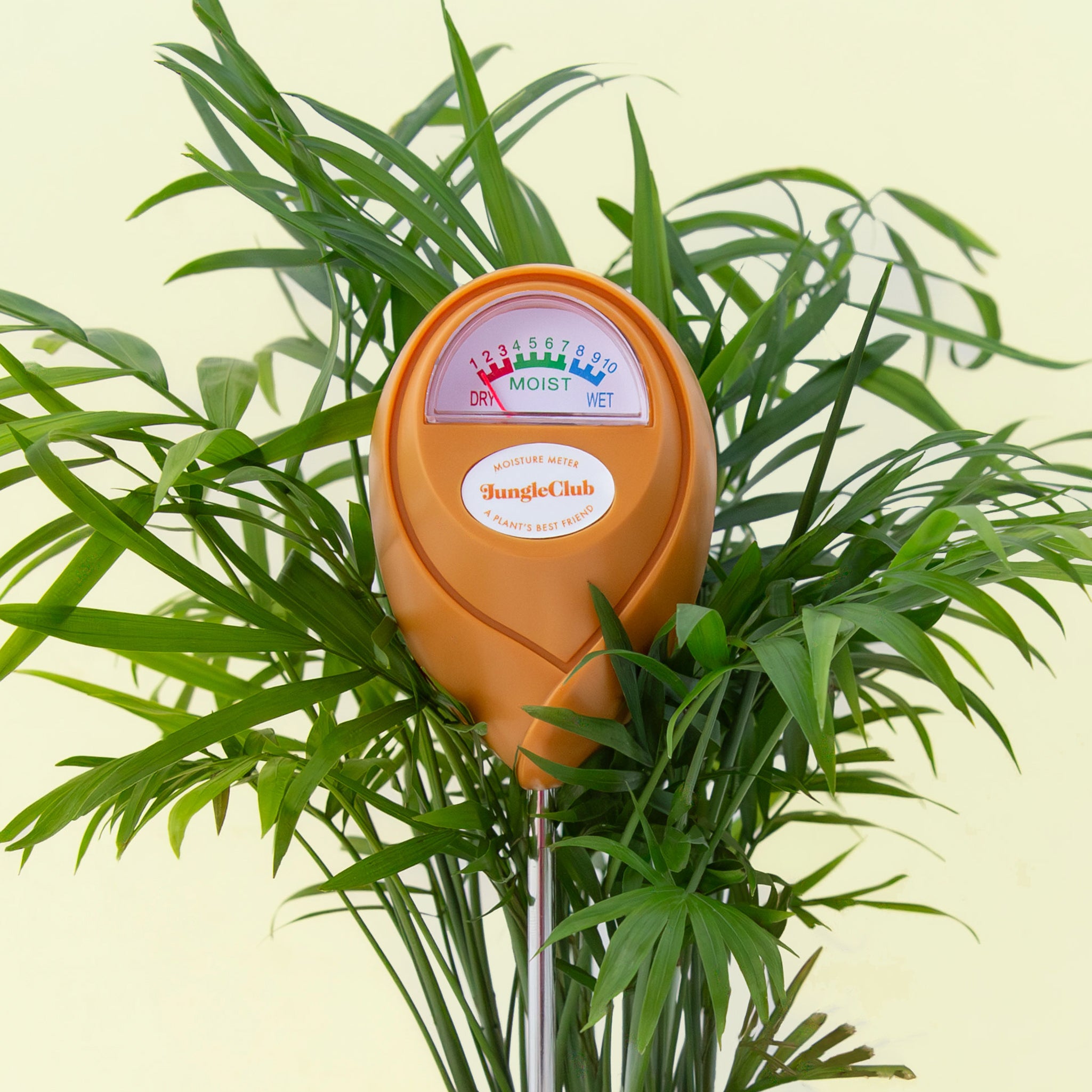 An orange moisture meter with a rounded head and a white meter that ranges from dry, moist, or wet along with a small oval label in the front that reads, "Jungle Club".