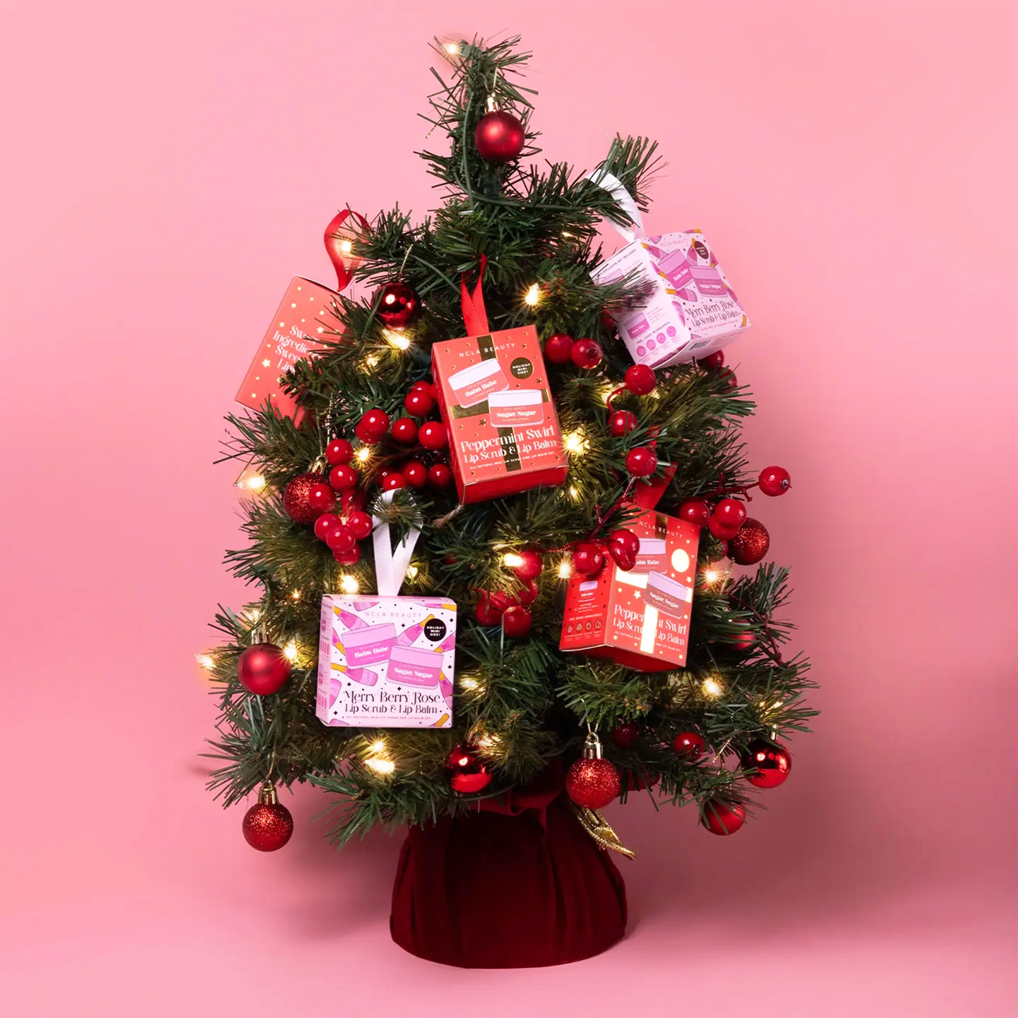 A set of one lip scrub and lip balm in a red package that is also a loop for hanging on a tree. 
