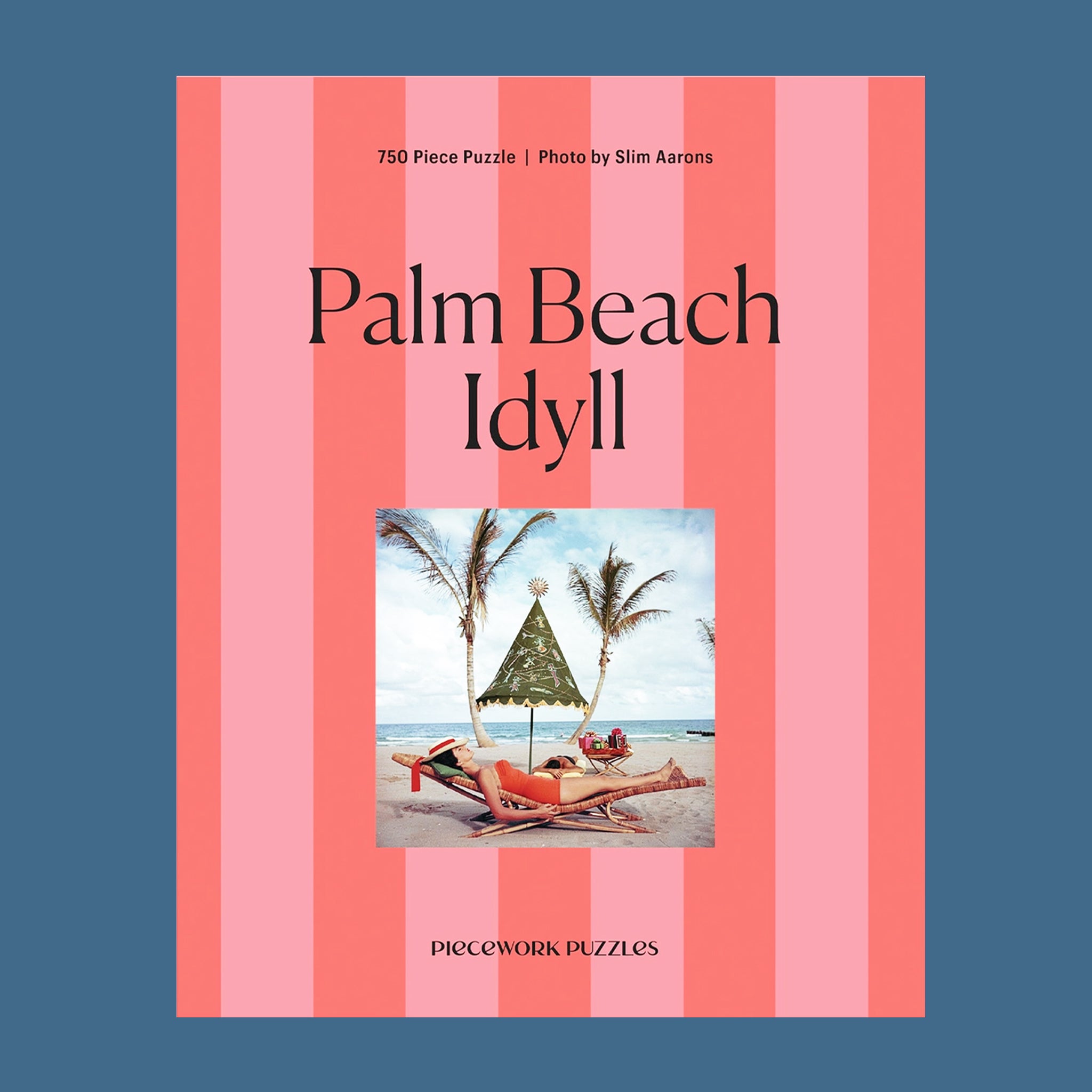 A pink striped boxed puzzle "Palm Beach Idyll" with an image of a retro beach scape. 