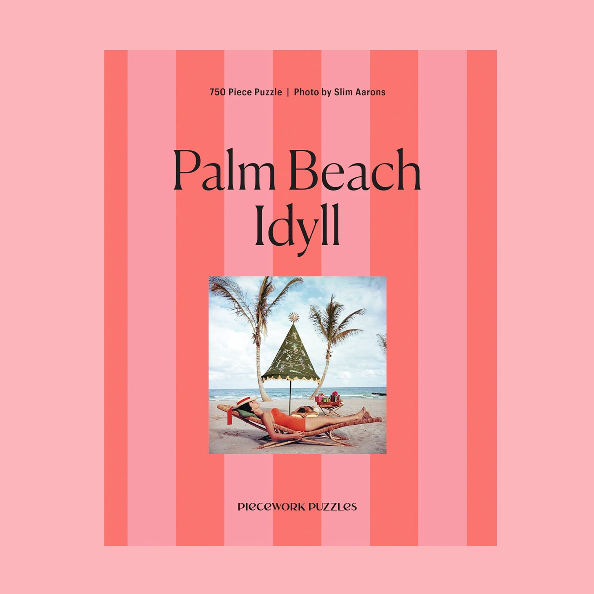 A pink striped boxed puzzle "Palm Beach Idyll" with an image of a retro beach scape. 