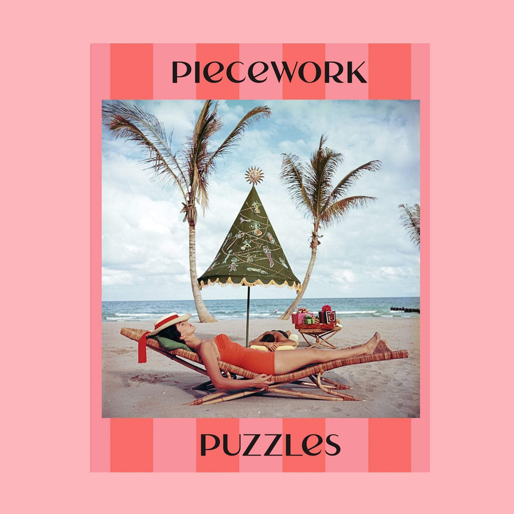 A pink striped boxed puzzle "Palm Beach Idyll" with an image of a retro beach scape. 