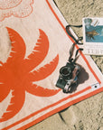 A beach towel with a palm tree design. 