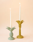 A yellow colored palm tree shaped taper candle holder. 