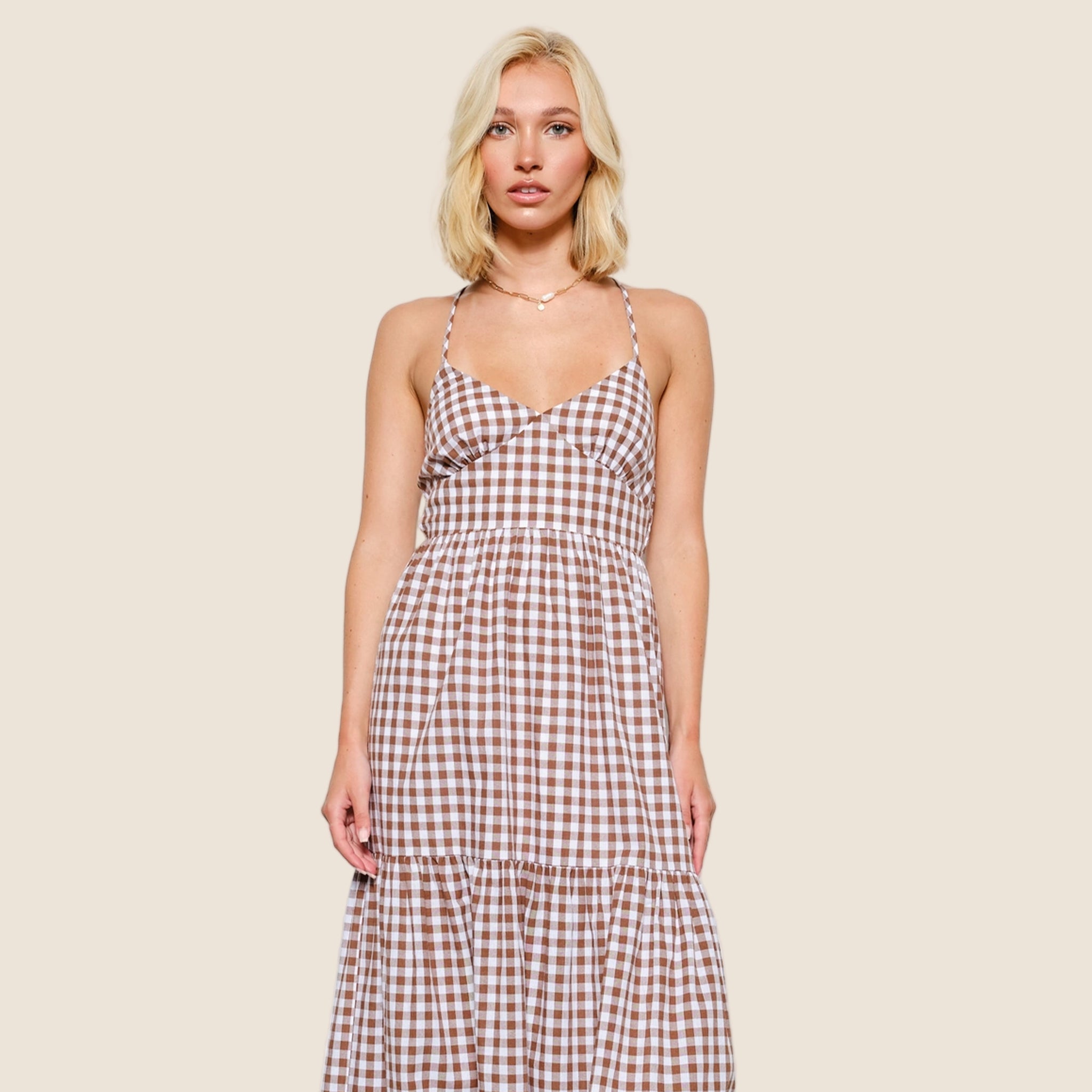 A brown and white gingham dress with spaghetti strap details and a cross back. 