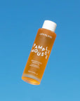 A bottle of orange body oil with white text that reads, 'Pamplemousse Replenishing Body Oil'. 