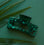 On a dark turquoise background is the Paradise Hair Claw in the shade Emerald which is a rectangle hair clip in an emerald green shade with a shell finish. 