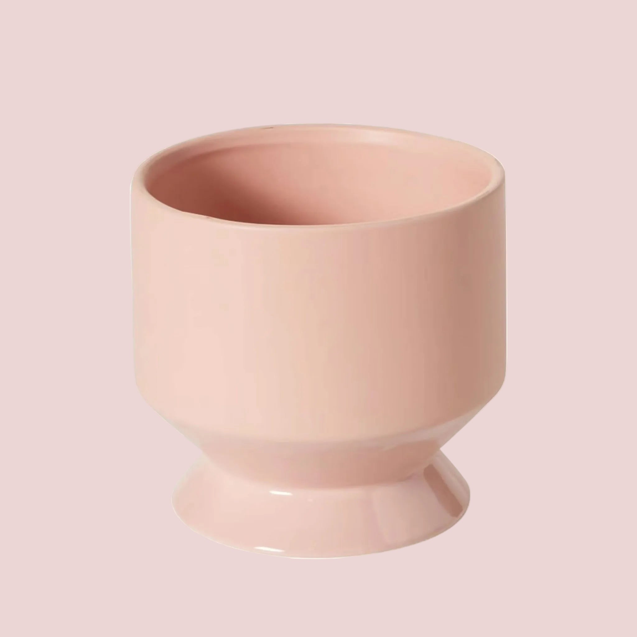 A peach colored ceramic pedestal planter. 