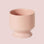A peach colored ceramic pedestal planter. 