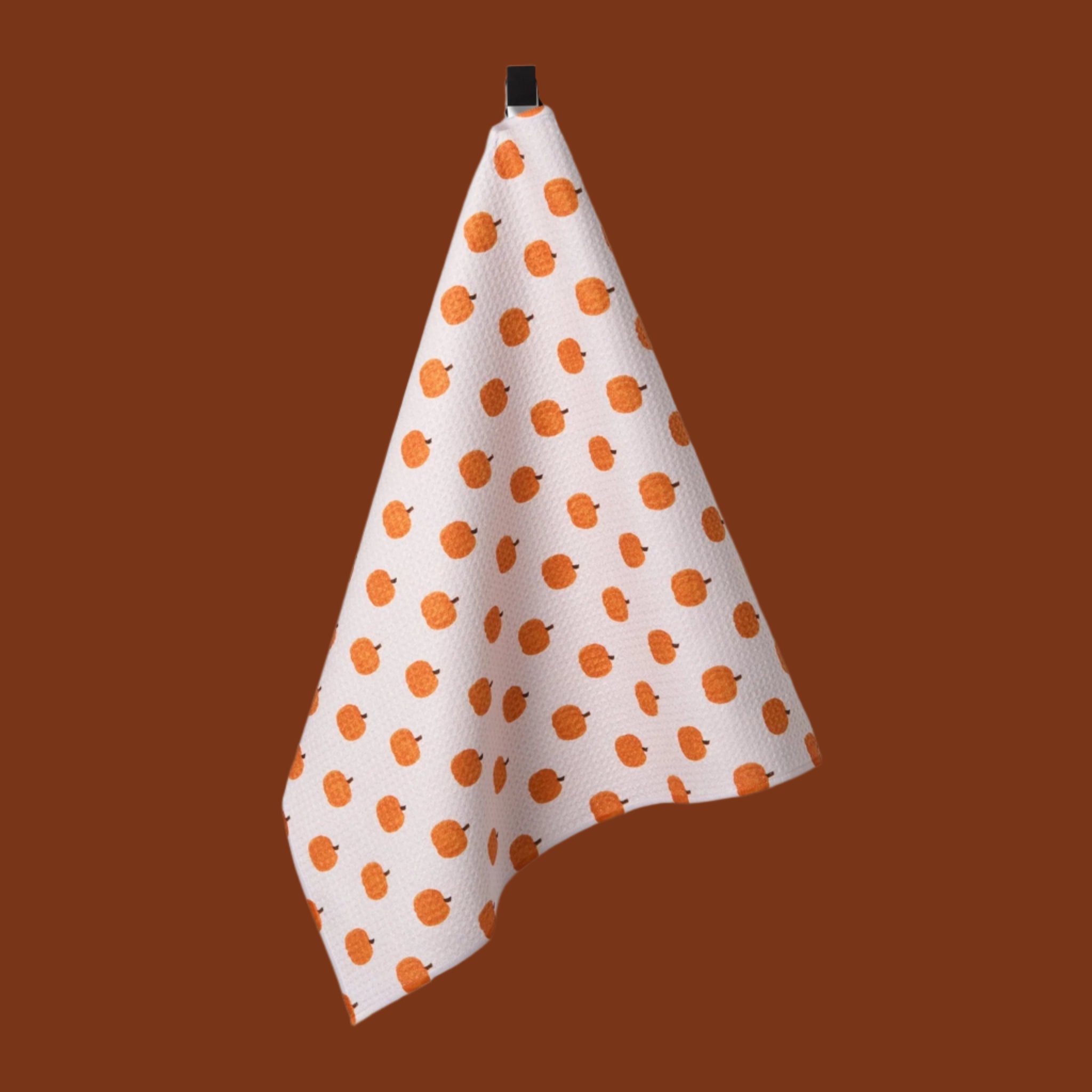 A white and orange pumpkin printed tea towel.